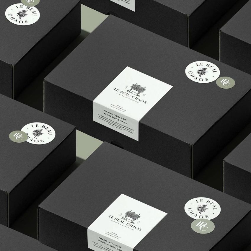 Sticker mockup featuring several black boxes arranged in a grid, each with round and rectangular white stickers on the lids.