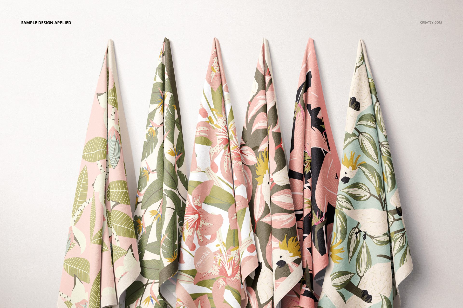 PSD mockup showing six pieces of fabric suspended, each with different soft-colored botanical prints, arranged in a row.