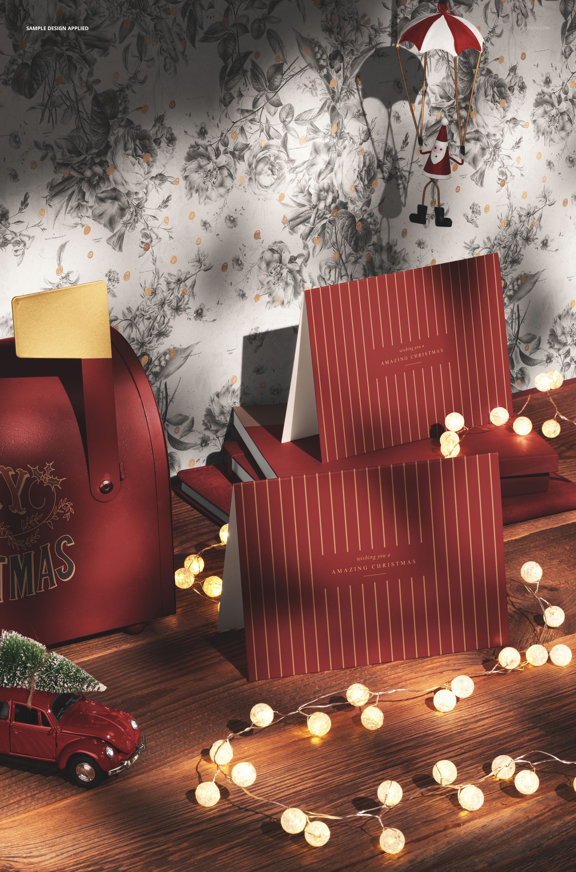 PSD mockup showing Christmas cards with vertical stripes, illuminated by string lights and set with seasonal ornaments.