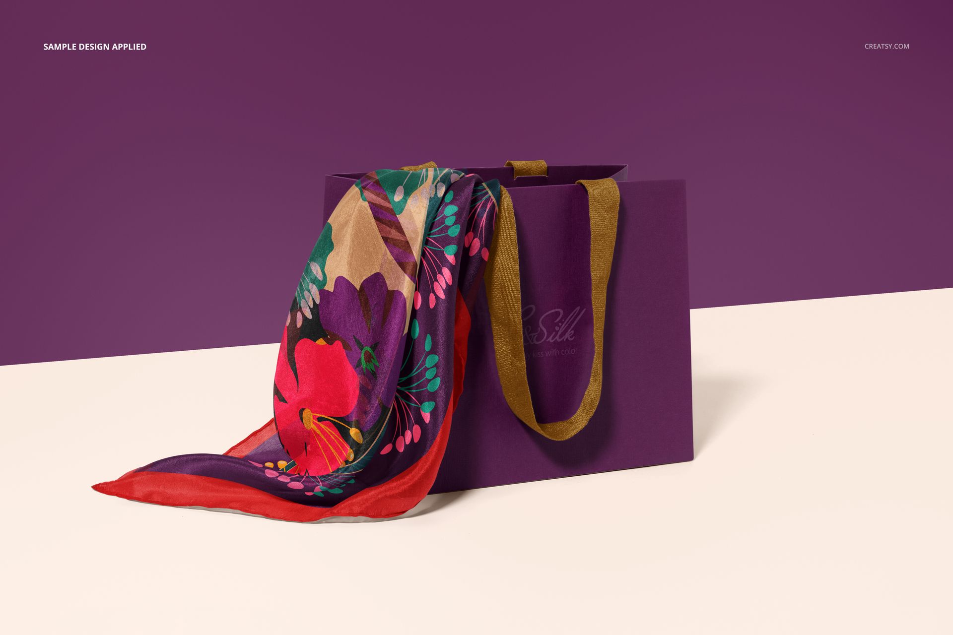 PSD mockup featuring a vibrant silk scarf with hand-rolled borders arranged over a purple gift bag, front perspective.