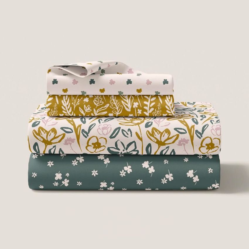 Folded bedding set mockup featuring three stacked pieces with floral and botanical patterns in green, gold, and white tones.