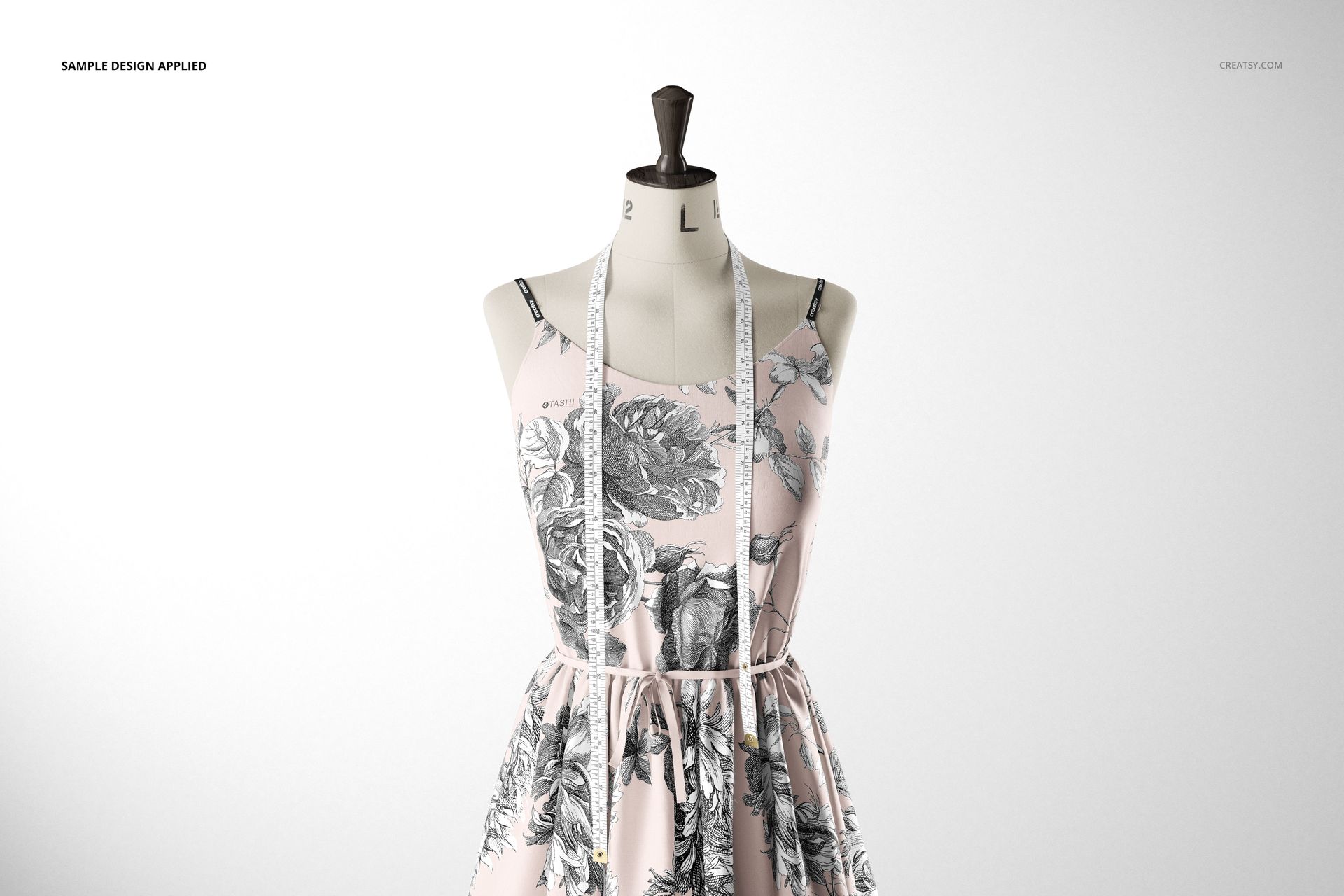Fabric dress mockup displayed on a mannequin, with a light background and monochrome botanical print, measuring tape visible.