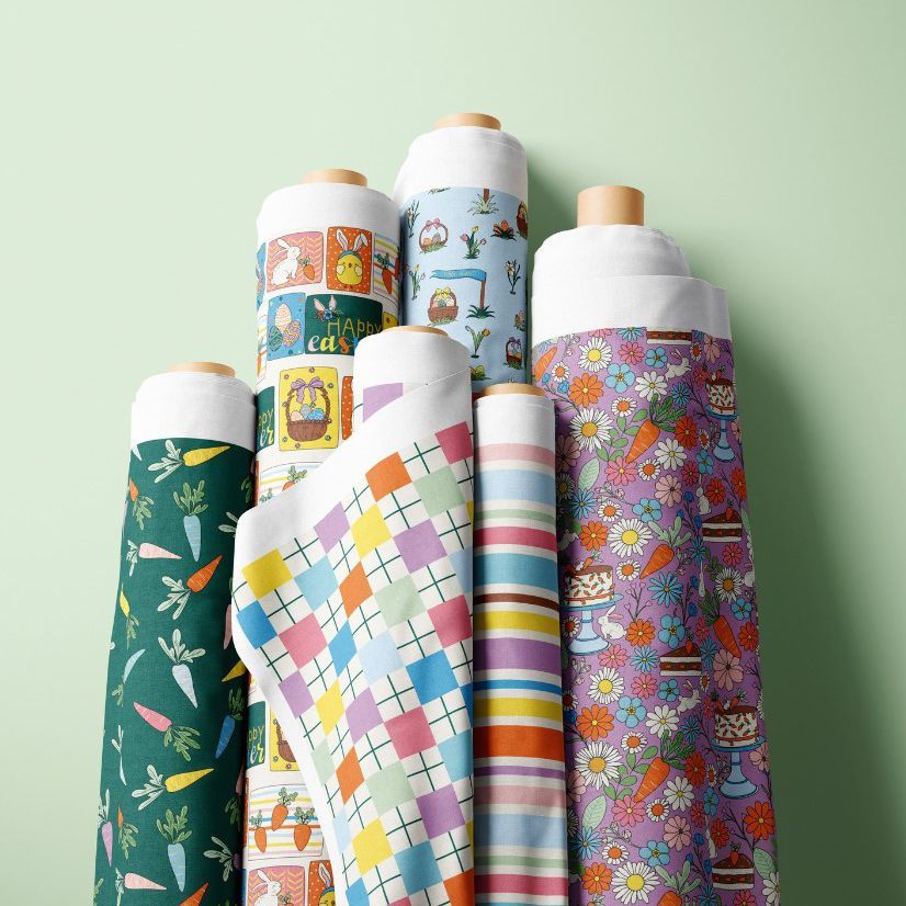 Fabric rolls mockup featuring seven upright rolls with colorful Easter and spring-themed patterns against a light green background.