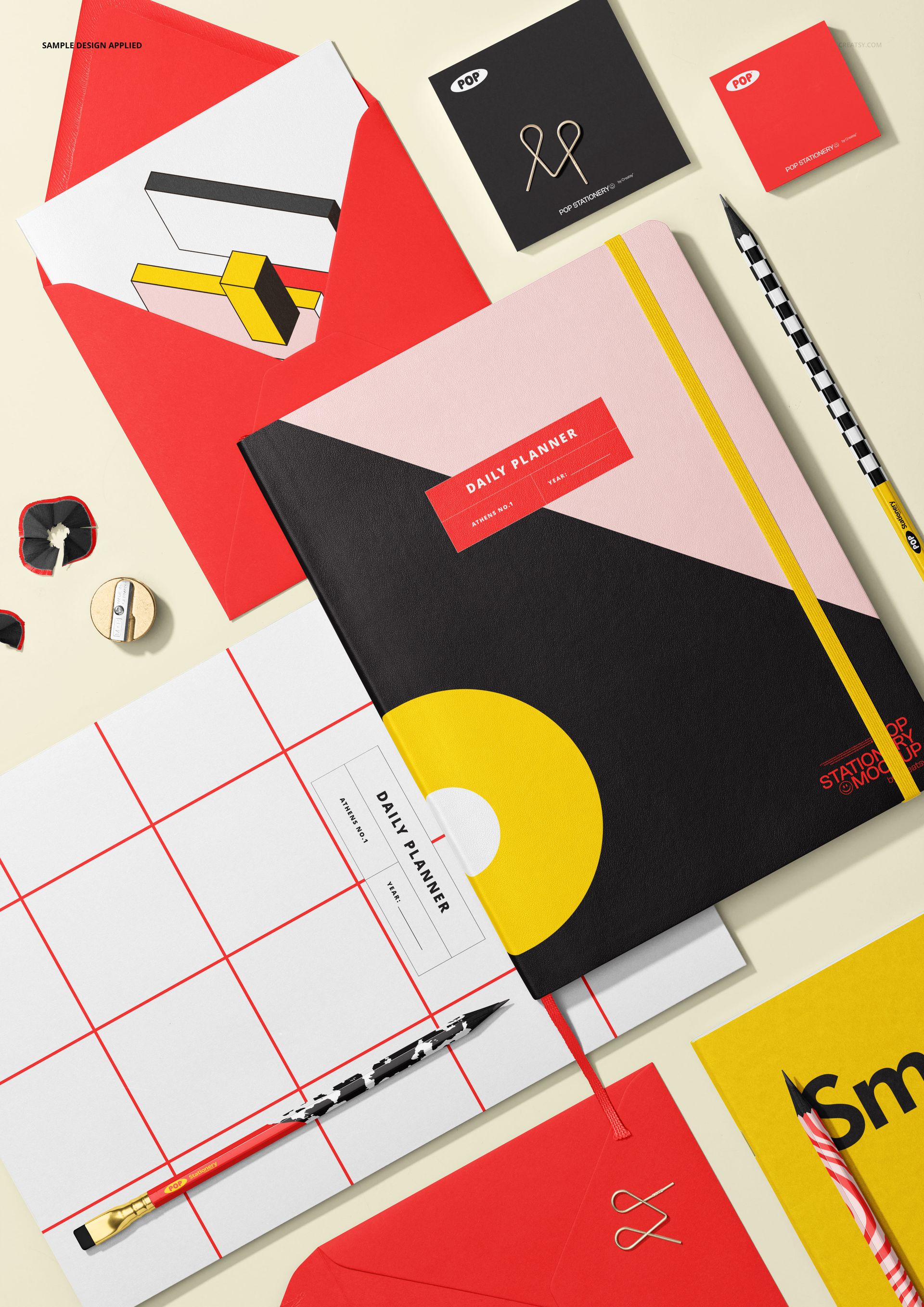 Top view of a stationery mockup featuring a daily planner, notebooks, envelopes, and writing tools in bold colors.