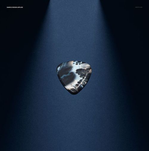 Guitar pick mockup featuring a marbled design, illuminated by focused beams of light against a deep blue backdrop.