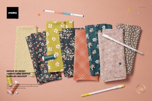 PSD mockup featuring folded jersey fabrics in floral and plaid designs, accompanied by sewing tools and accessories.