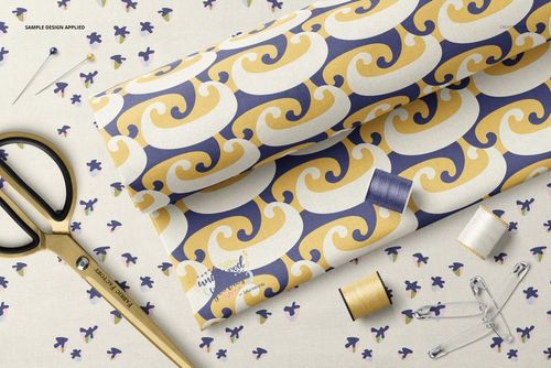 Flat lay of patterned cotton fabric mockup with scissors, pins, and spools of thread on a light background.