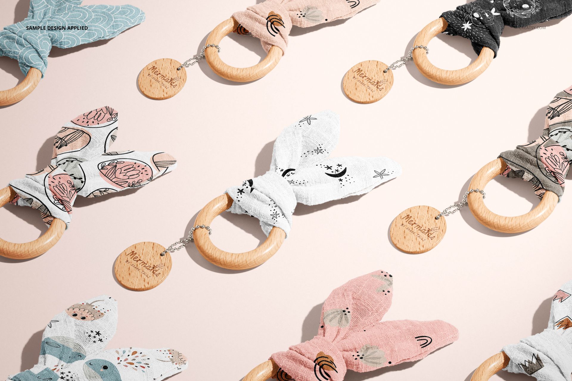 Assorted wooden baby teether mockups featuring soft fabric bunny ears in various colors and playful prints, flat lay.