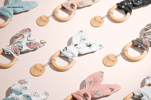 Assorted wooden baby teether mockups featuring soft fabric bunny ears in various colors and playful prints, flat lay.