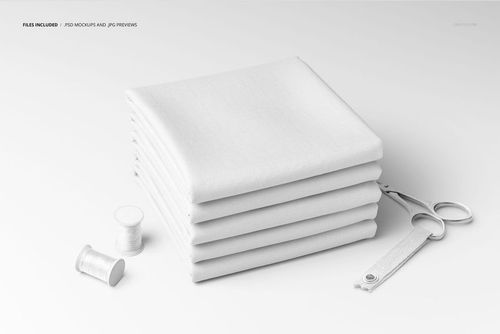 Front view of a fabric stack mockup showing six folded white textiles with sewing scissors and thread spools beside them.