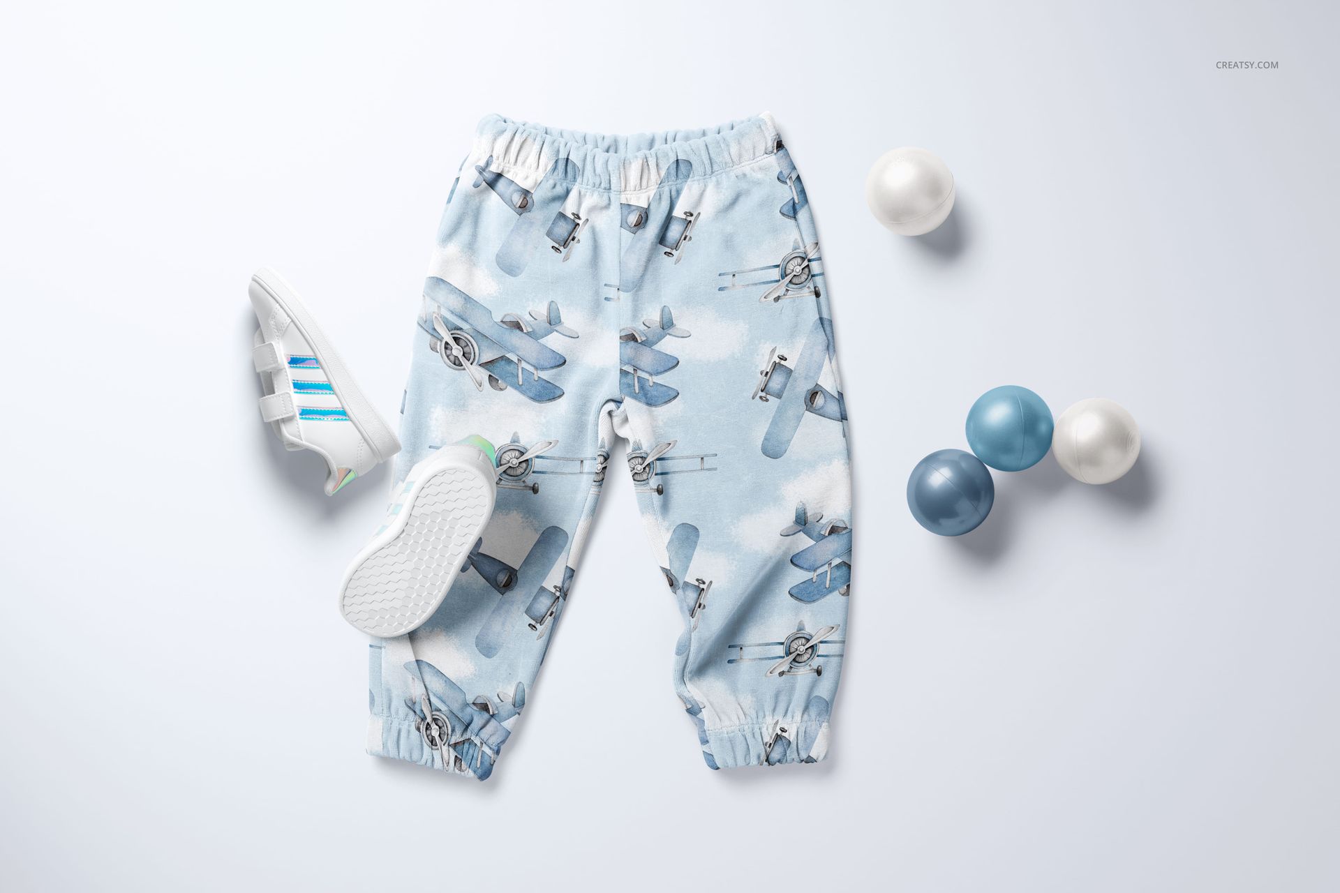 PSD mockup of baby sweatpants in a sky-themed design, shown with blue and white balls and a pair of small sneakers.