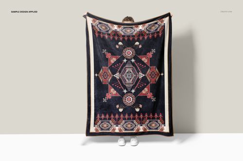 Front view of a fleece throw blanket mockup featuring a bold geometric design in dark and earthy tones, held by a person.