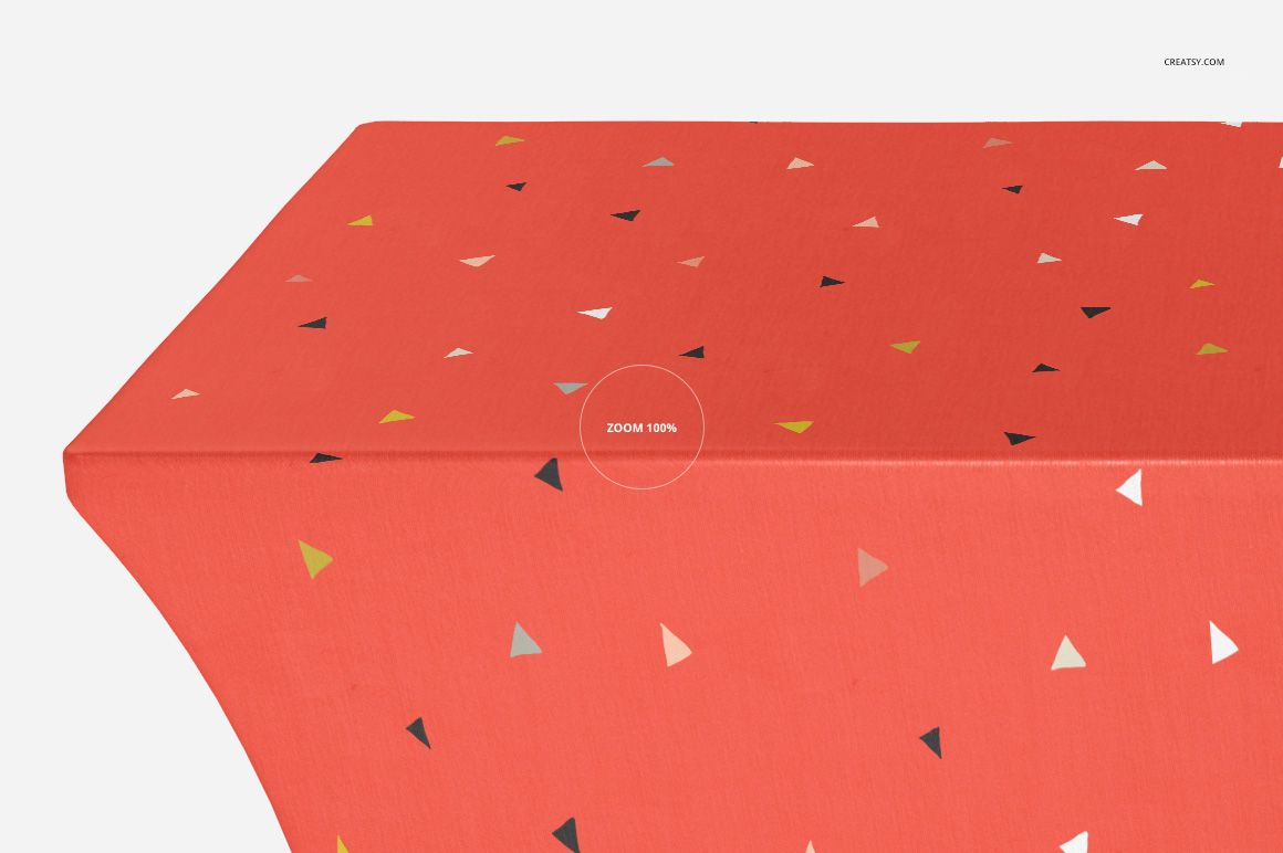 Close-up of a custom tablecloth mockup featuring coral red fabric with multicolored triangles, shown from the side.