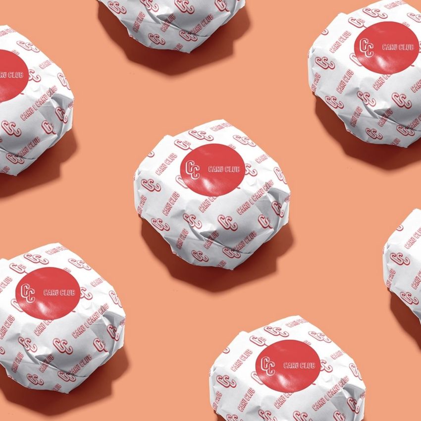 Burger mockup featuring multiple wrapped burgers on a peach background, with white paper printed with red logos and text.