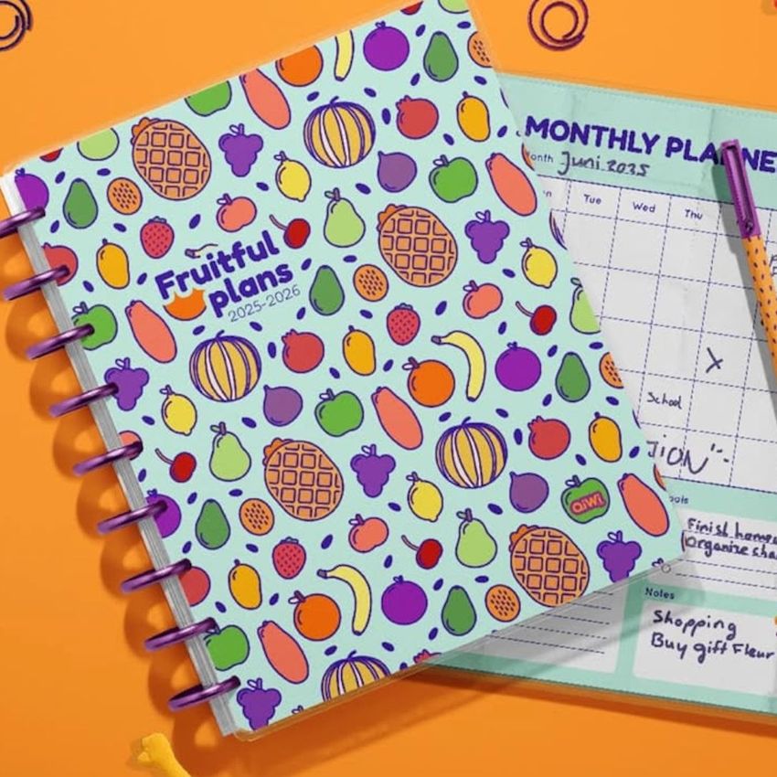 Stationery mockup showing a closed planner with a playful fruit pattern and an open planner displaying a monthly schedule.