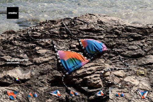 Bikini mockup with multicolored top and bottom, striped ties, laid out on textured rocks in natural sunlight.