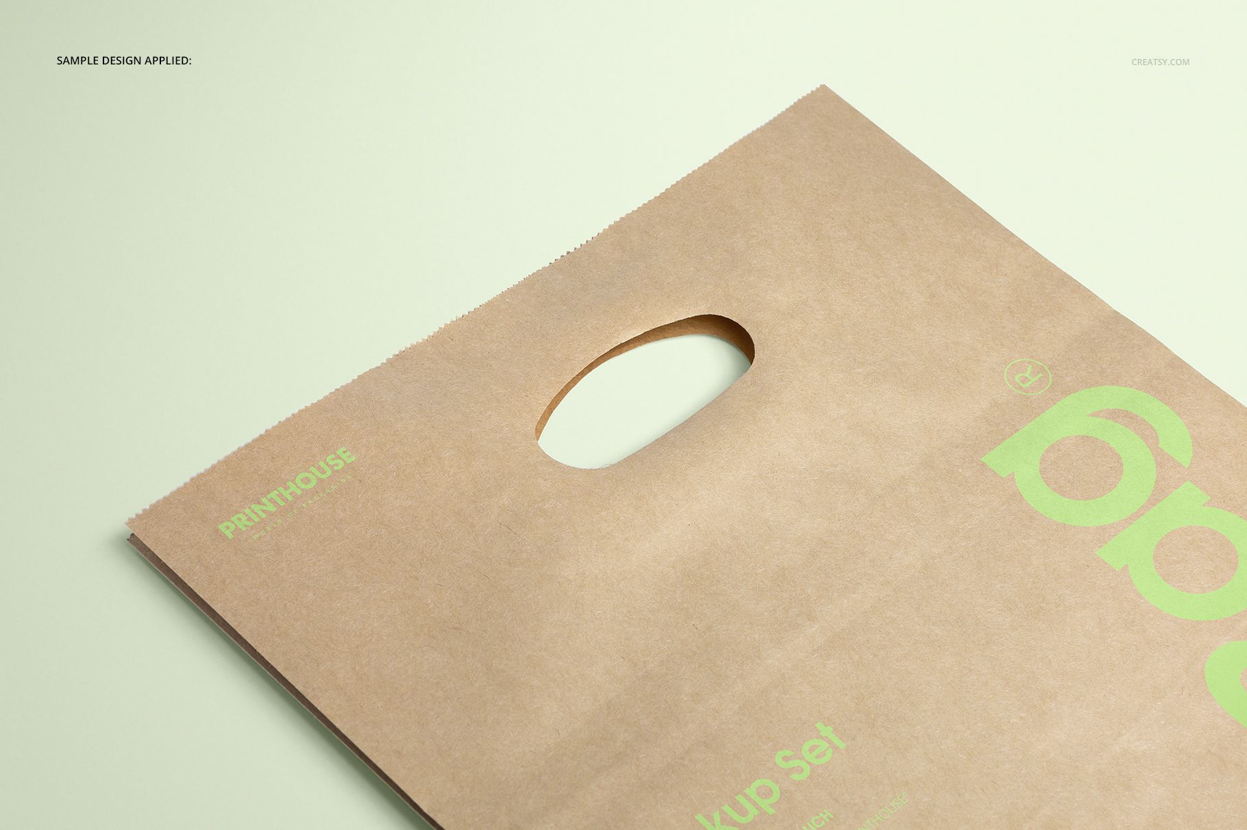 Front view of a die cut kraft paper bag mockup with a handle, featuring light brown color and green print details.