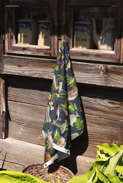 Patterned fabric mockup draped over a wooden windowsill, featuring tropical birds and green foliage in sunlight.