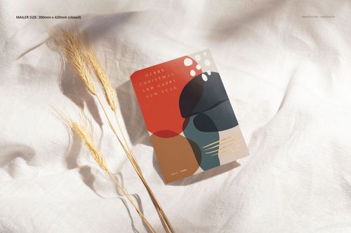 Mockup of a stationery card with modern abstract design, surrounded by natural dried wheat on a soft fabric background.