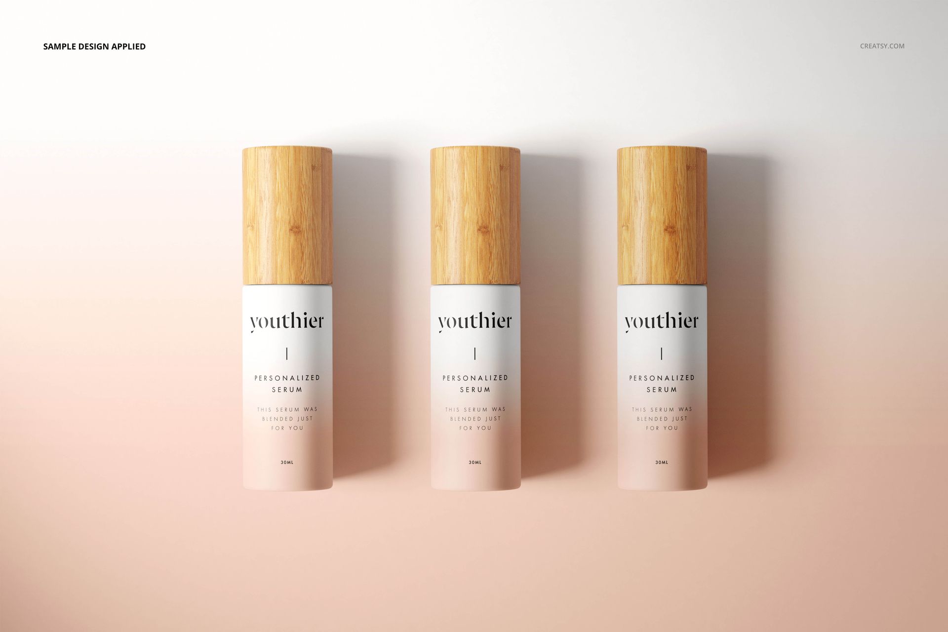 PSD mockup showing three upright cosmetic bottles with bamboo-style lids and pale pink gradient labels.