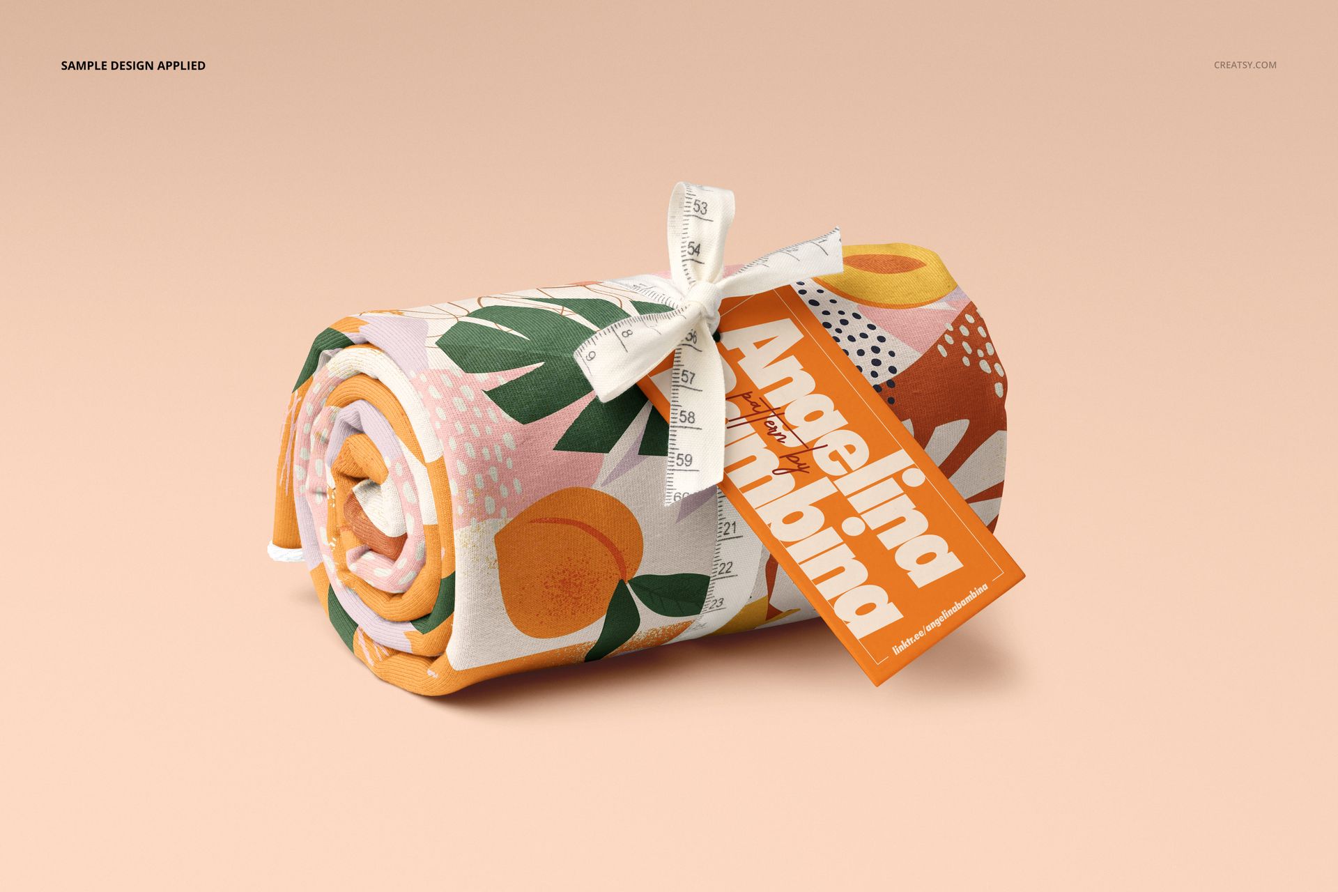 Jersey fabric roll featuring a vibrant peach and leaf design, secured with a measuring tape and orange label, mockup scene.