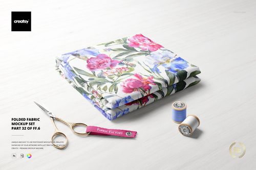 Folded floral fabric mockup on a pale tabletop, featuring sewing scissors and two thread spools beside the material.