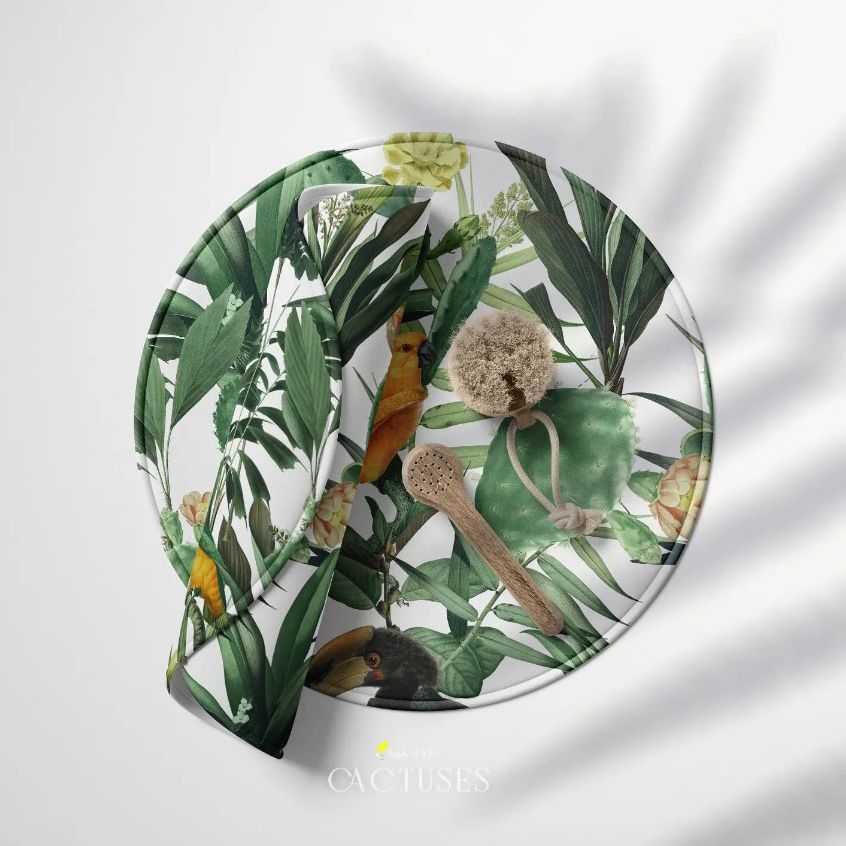 Round polyester bath mat mockup with a tropical leaf and bird pattern, shown with a bath brush and sponge on a white surface.