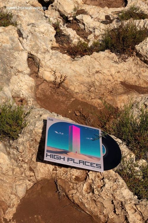 Top view of a 7 inch vinyl record mockup featuring vibrant artwork, lying on textured rocky ground outdoors.