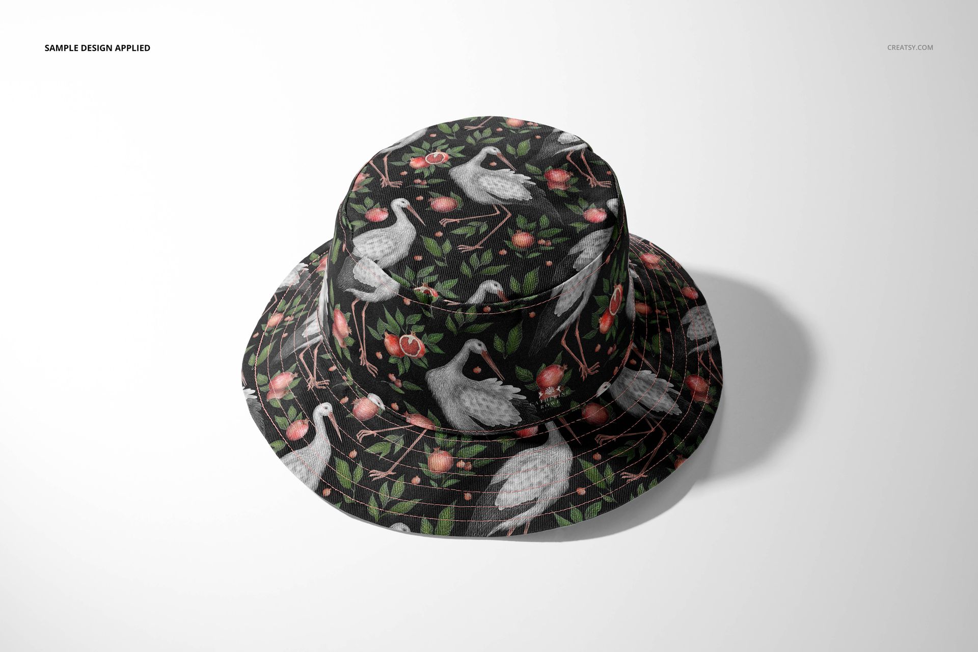 Front view of a reversible bucket hat mockup featuring a dark background with crane and floral pattern on a plain surface.