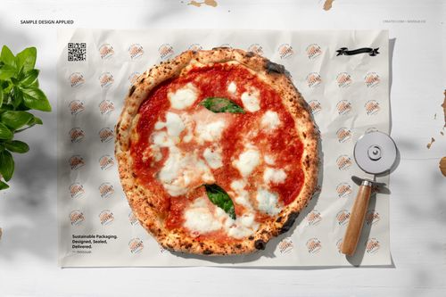 Mockup scene featuring a pizza on printed food safe paper, pizza cutter on the side, and natural light casting shadows.