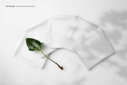 PSD mockup showing five folded white silk scarves in a top-down perspective with a single green leaf nearby.