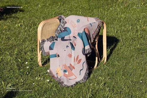 Jacquard fringed throw blanket mockup featuring playful shapes and colors, displayed on a chair in a grassy yard.