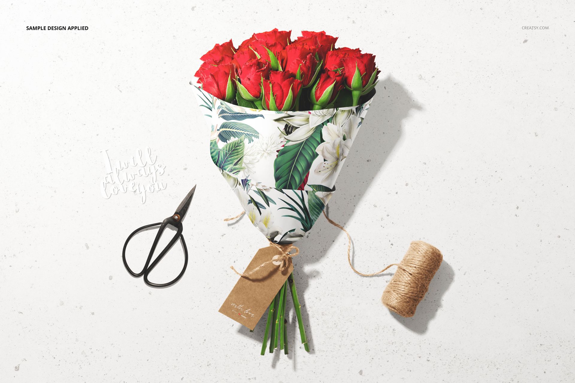 PSD mockup featuring a bouquet of red roses in decorative wrapping, accompanied by scissors, twine, and a blank kraft tag.