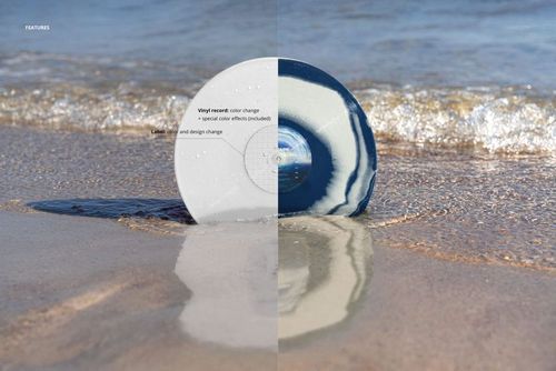 Vinyl record partially buried in beach sand with ocean waves in the background, front view mockup scene.