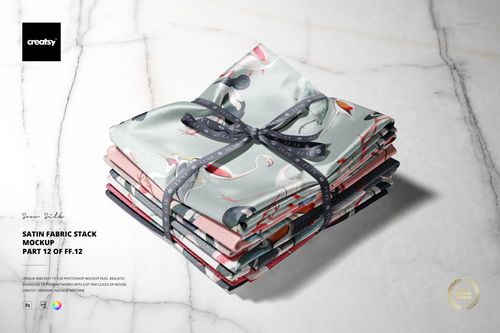 Satin fabric stack mockup showing several folded textiles with different prints arranged neatly on a marble background.