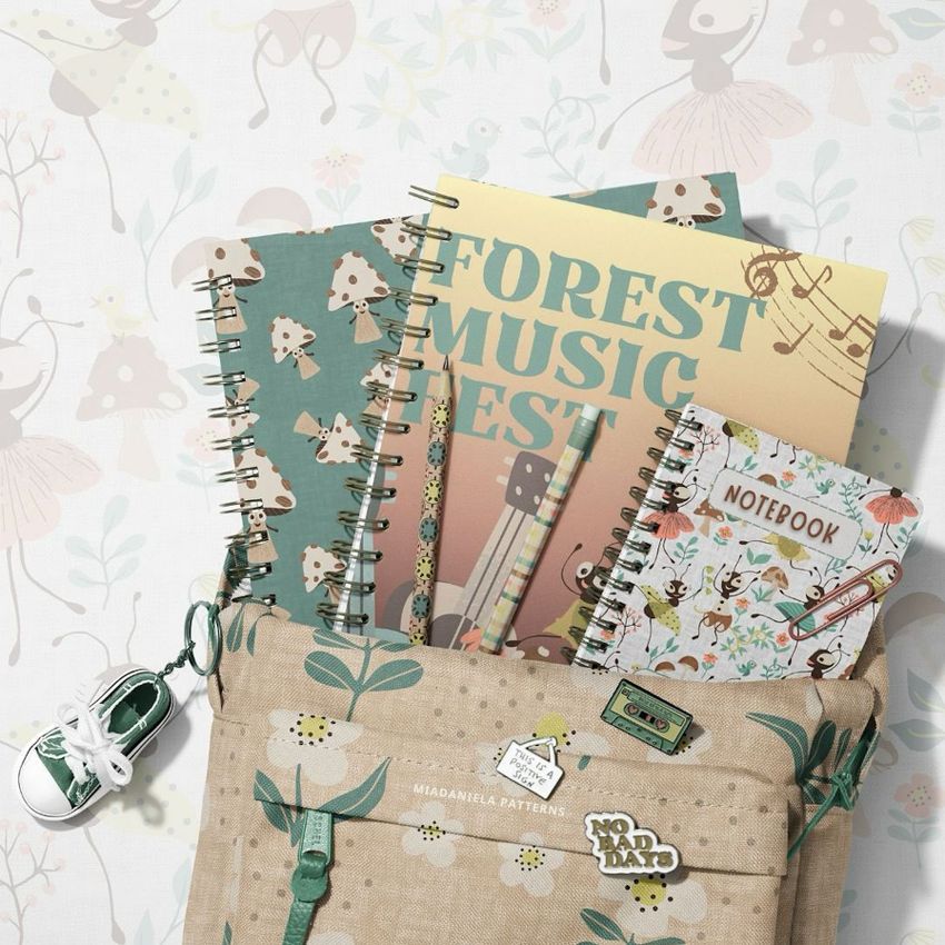 School backpack mockup with spiral notebooks featuring whimsical animal and mushroom patterns, viewed from above on a light background.