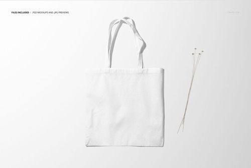 White tote bag mockup displayed from the front, set against a minimal light backdrop with dried stems beside it.