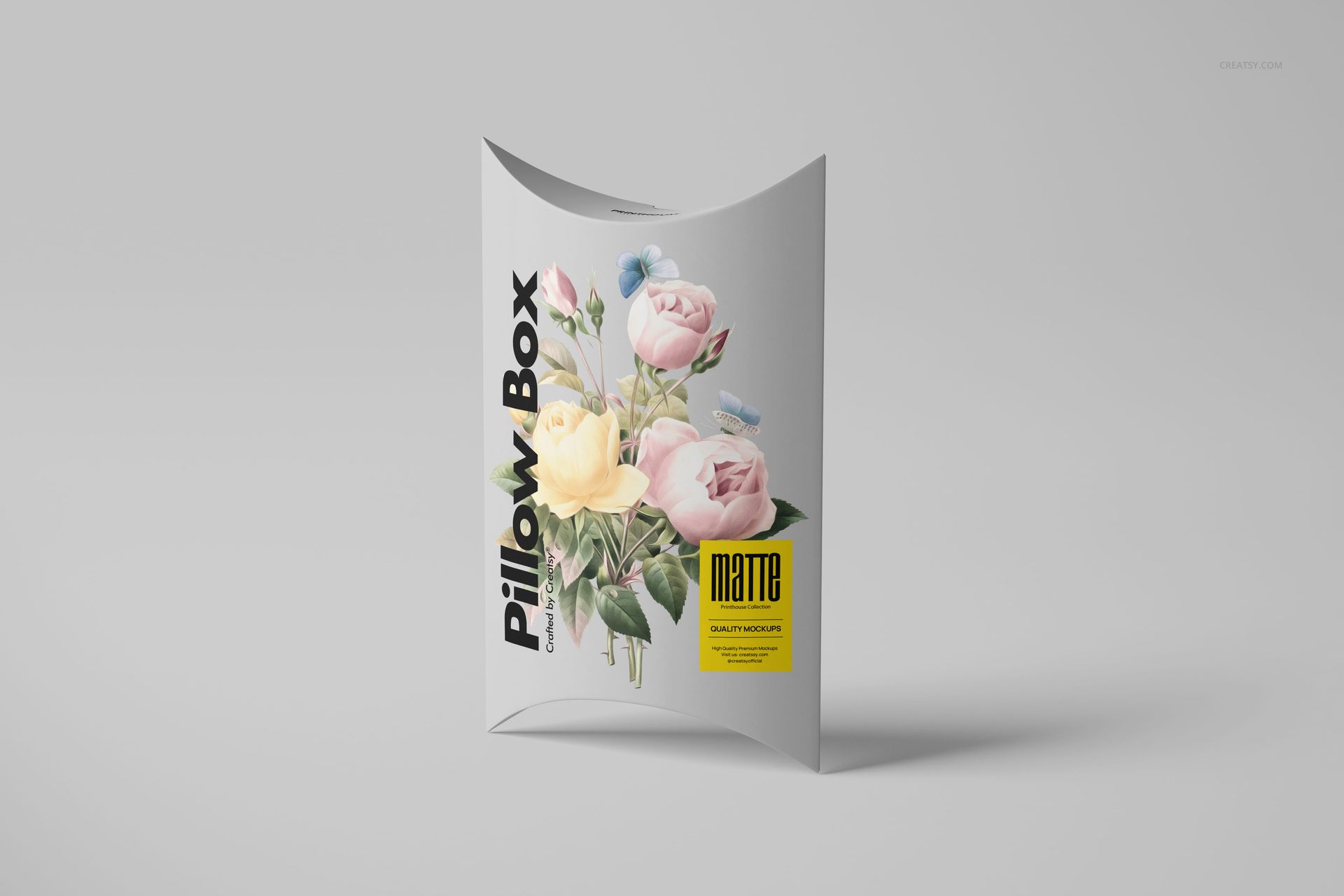 Matte pillow box with floral illustration, standing upright on a light gray surface, front view mockup.