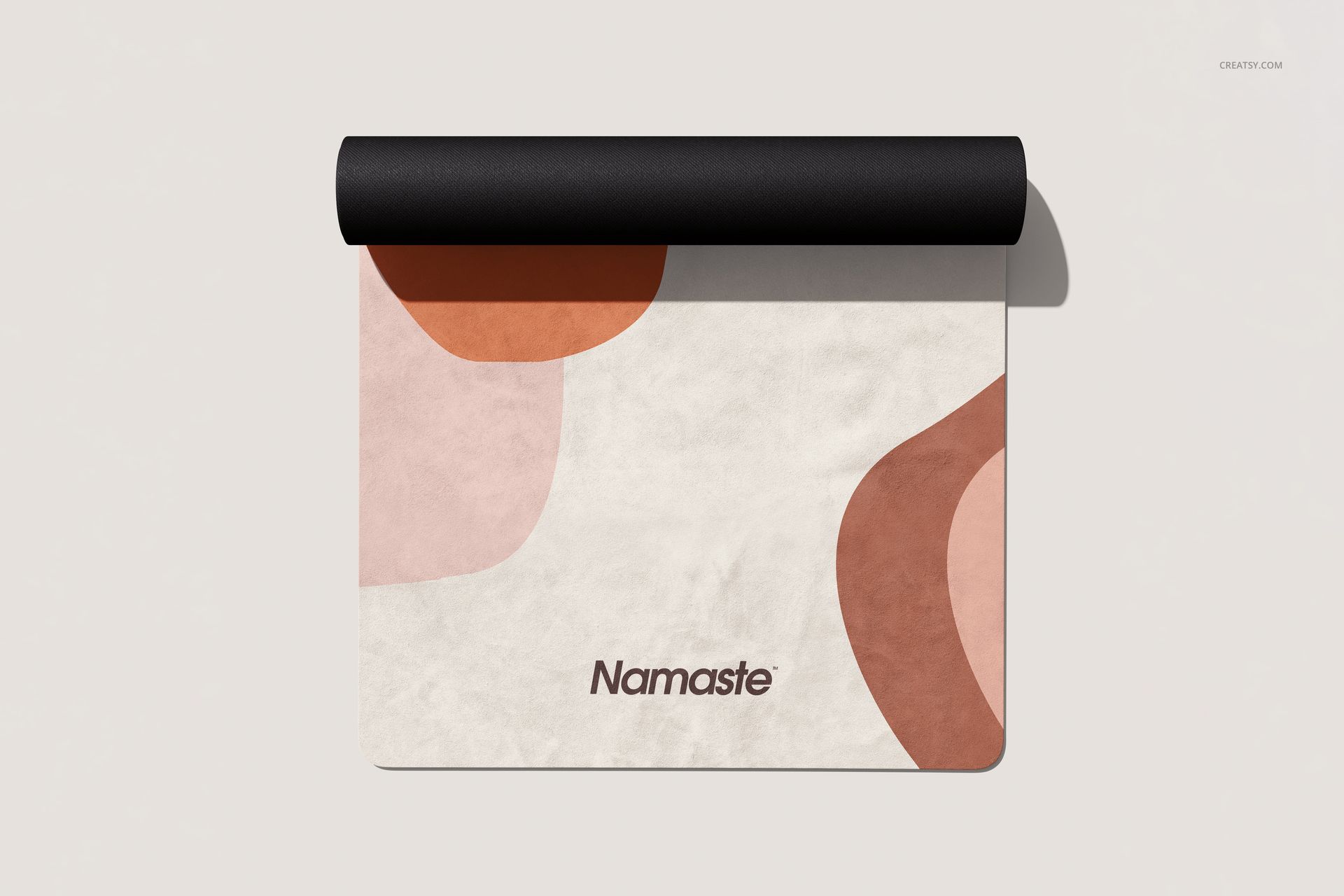 Rolled black yoga mat mockup featuring soft geometric pattern in earth tones, displayed from a top perspective.