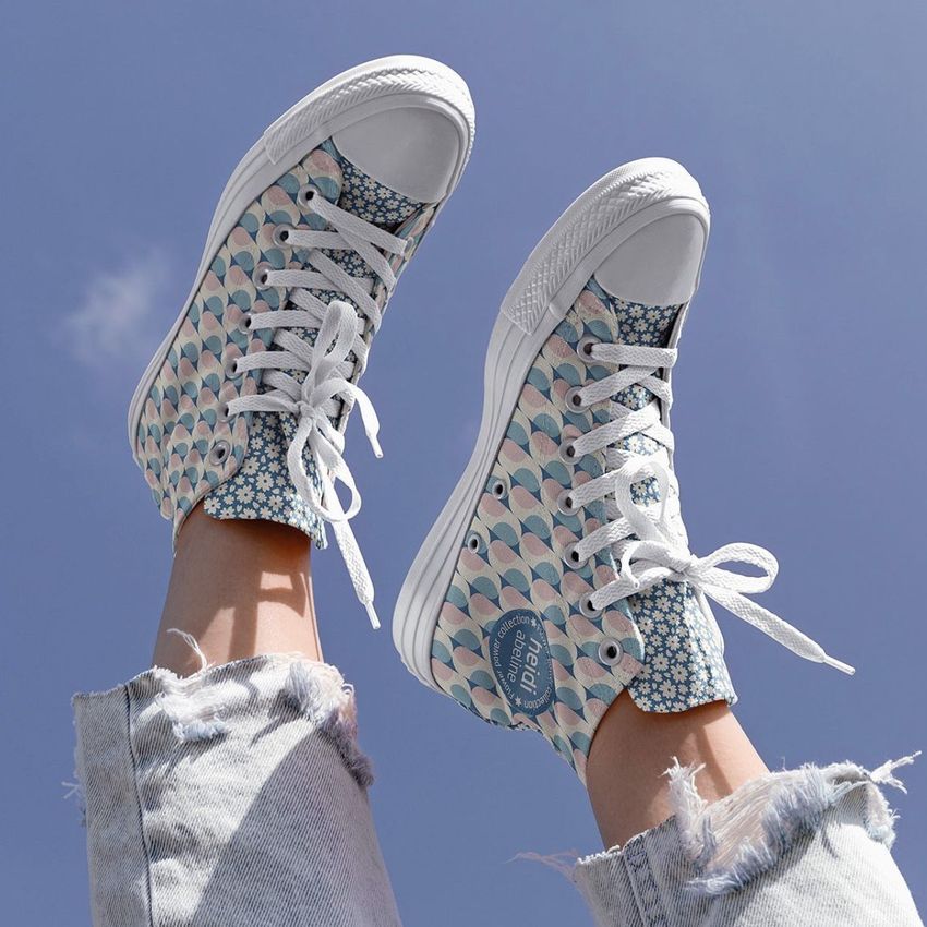 Sneakers mockup featuring a pair of patterned shoes with pastel blue and pink floral designs, worn outdoors against a blue sky.