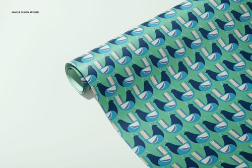 Gift wrapping paper mockup featuring a repeating blue bird design, displayed partially unrolled on a pale surface.