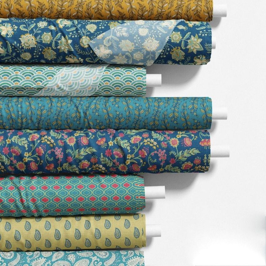 Fabric rolls mockup featuring eight patterned fabrics in blue, yellow, and teal tones, arranged horizontally on a white surface.