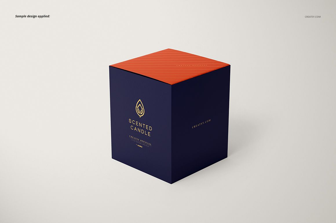 Classic candle mockup featuring a cube-shaped box with navy blue sides, orange lid, and gold text, front perspective.
