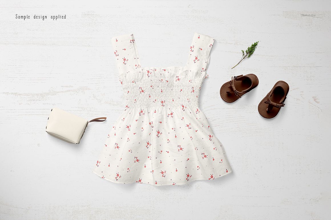 PSD mockup of a baby summer outfit featuring a white dress with red flowers, brown sandals, and a light purse on wood.