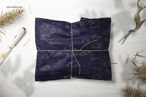 PSD mockup of gift wrapping tissue paper featuring a navy and gold design, surrounded by pen, scissors, and twigs.
