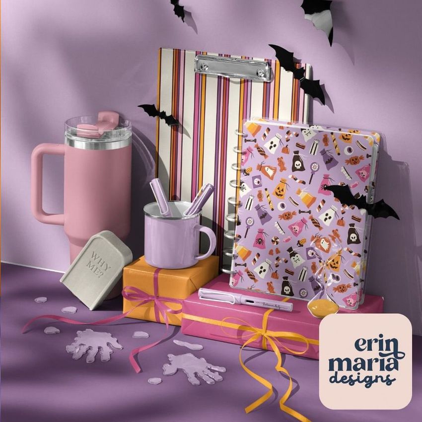 Halloween-themed desk stationery and drinkware mockup featuring a pink tumbler, purple mug, notebooks with festive patterns, and bat decorations on a lavender surface.