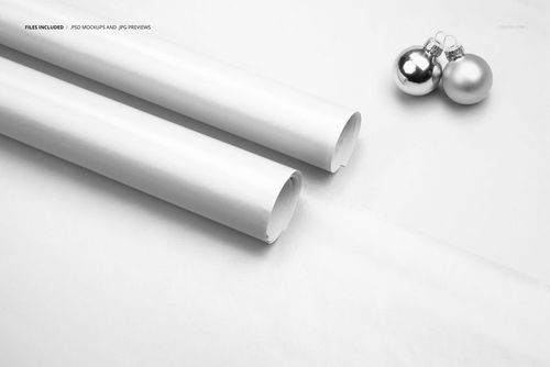 PSD mockup showing two plain wrapping paper rolls and silver Christmas ornaments arranged on a smooth, light backdrop.