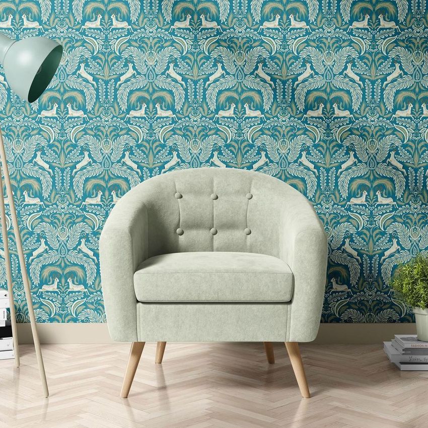 Interior scene mockup featuring a light green armchair with wooden legs set against a blue and gold Victorian-style patterned wallpaper.
