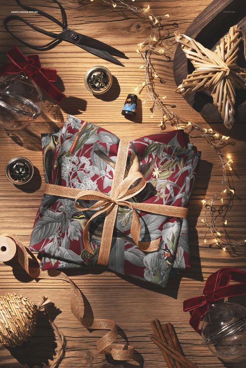 Christmas-themed folded jersey fabric mockup with a ribbon, surrounded by ornaments, fairy lights, and craft supplies.