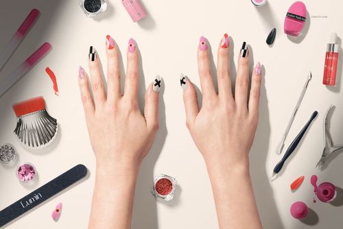 Nails mockup showing hands with creative nail designs and beauty products arranged on a light background.
